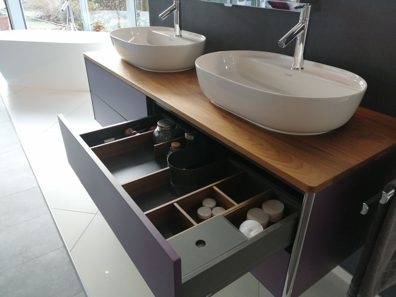 Ein Badezimmerwaschtisch mit zwei Waschbecken und offenen Schubladen