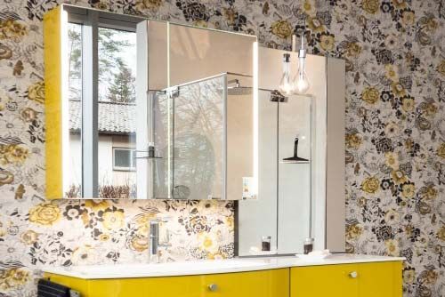 Ein Badezimmer mit gelben Schränken und einem Spiegel an der Wand.
