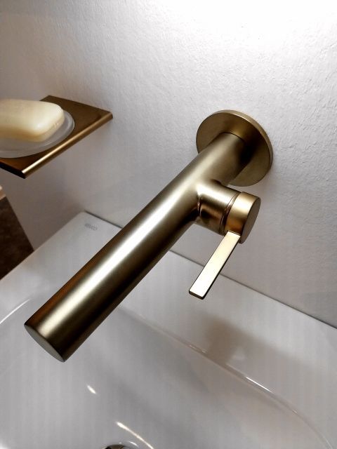 Ein Waschbecken mit einem goldenen Wasserhahn und einer Seifenschale