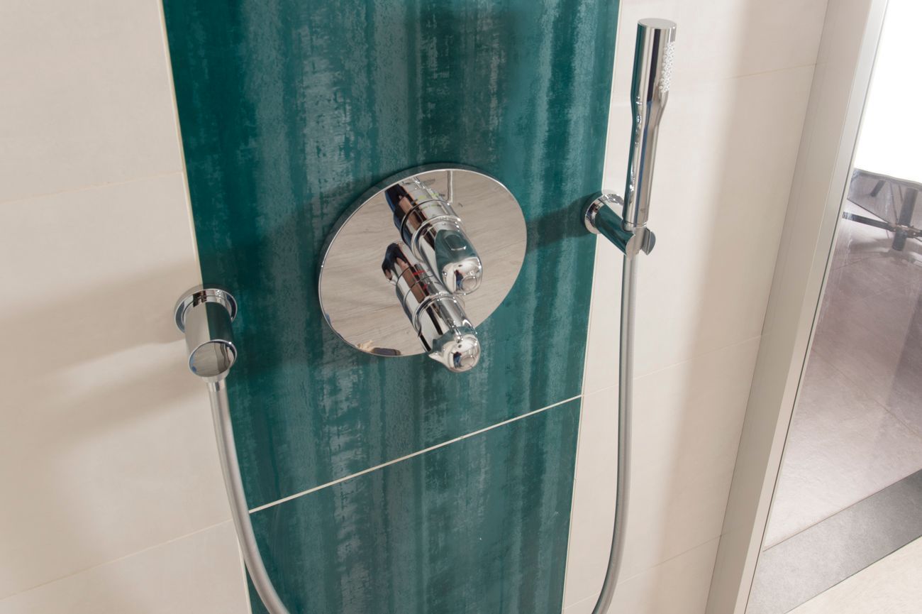 In einem Badezimmer hängt ein Duschkopf an der Wand.