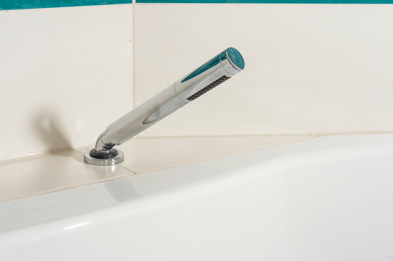 Ein Duschkopf ist an der Seite einer Badewanne angebracht.