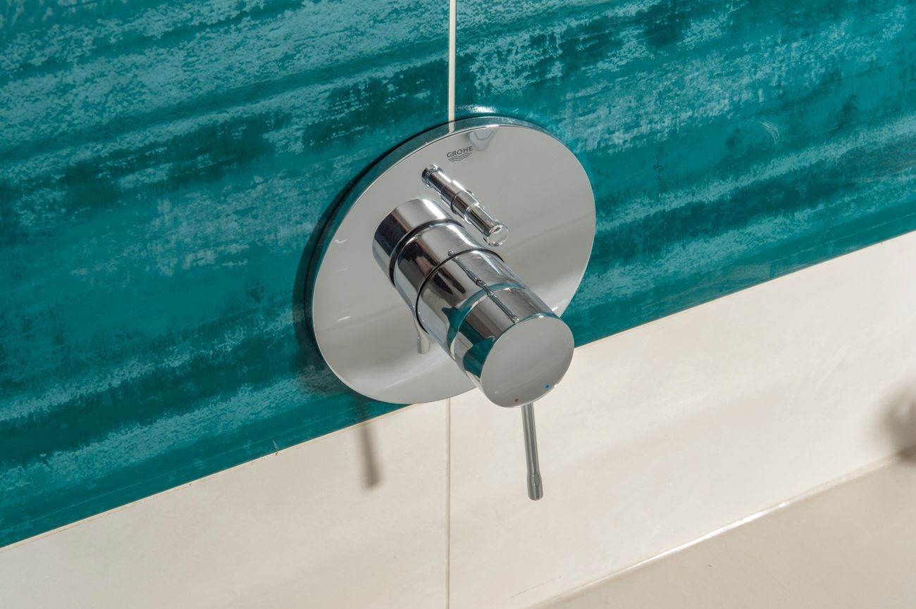 Eine Nahaufnahme eines Duschhahns an einer blau-weiß gefliesten Wand.