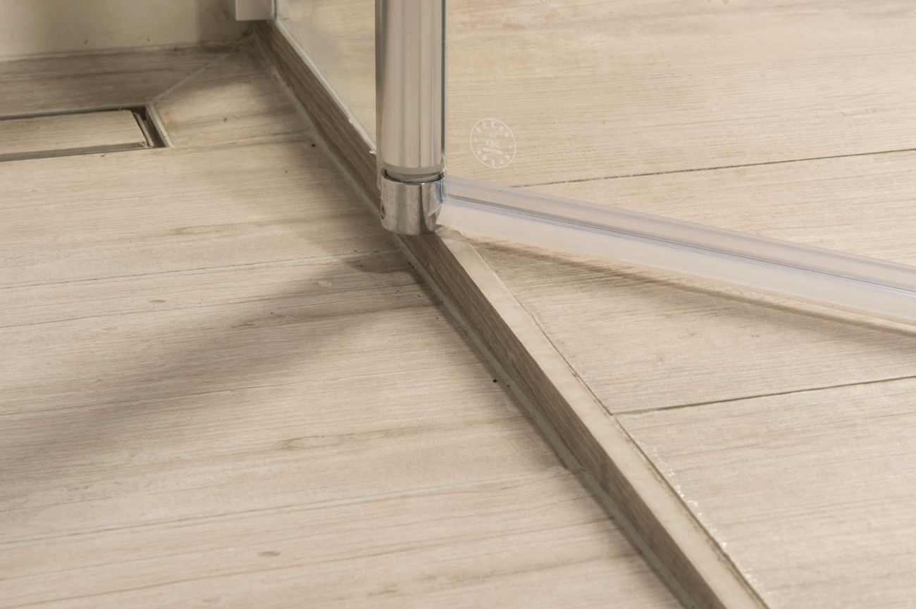 Eine Nahaufnahme einer Duschtür auf einem gefliesten Boden.