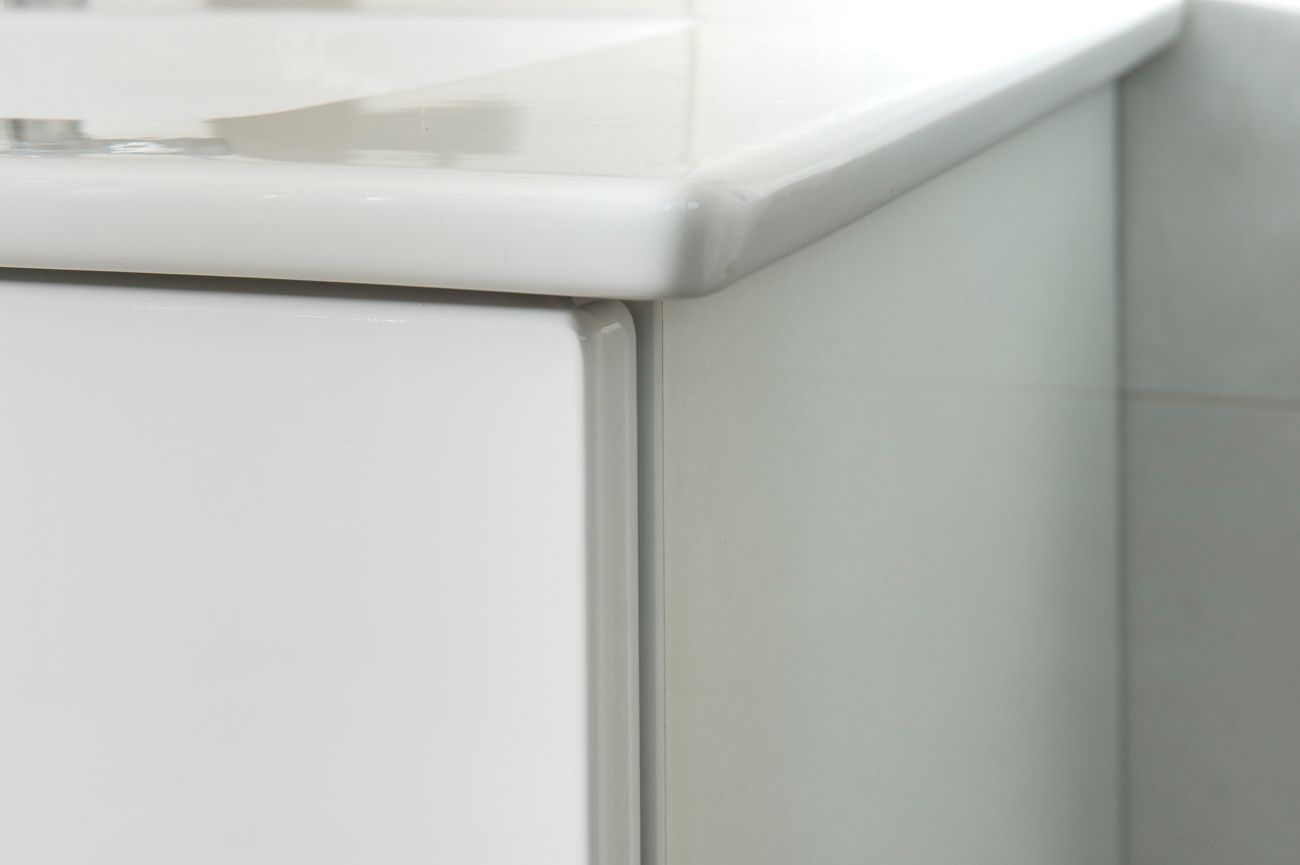 Eine Nahaufnahme eines weißen Schranks mit einem Waschbecken im Hintergrund