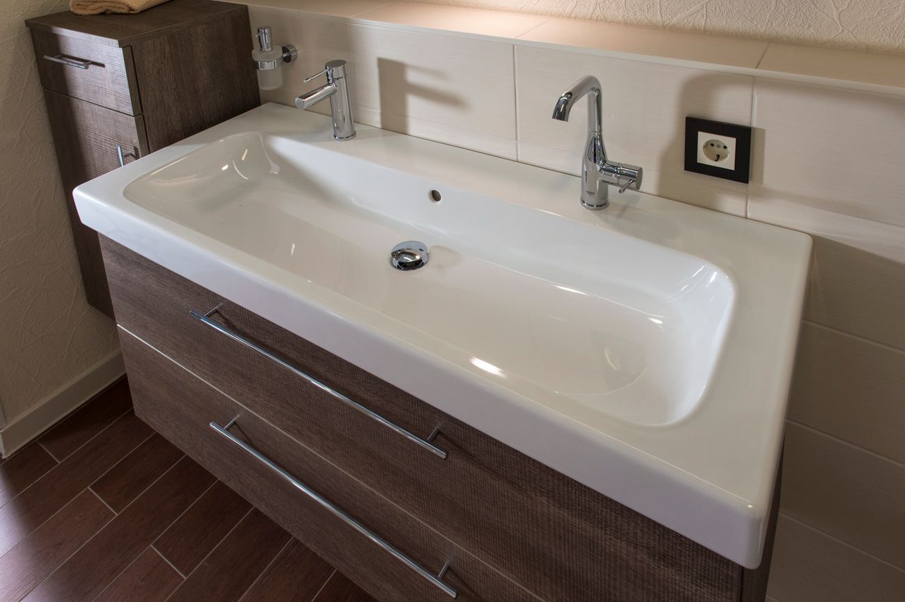 Ein Waschbecken mit Wasserhahn und Schubladen darunter.