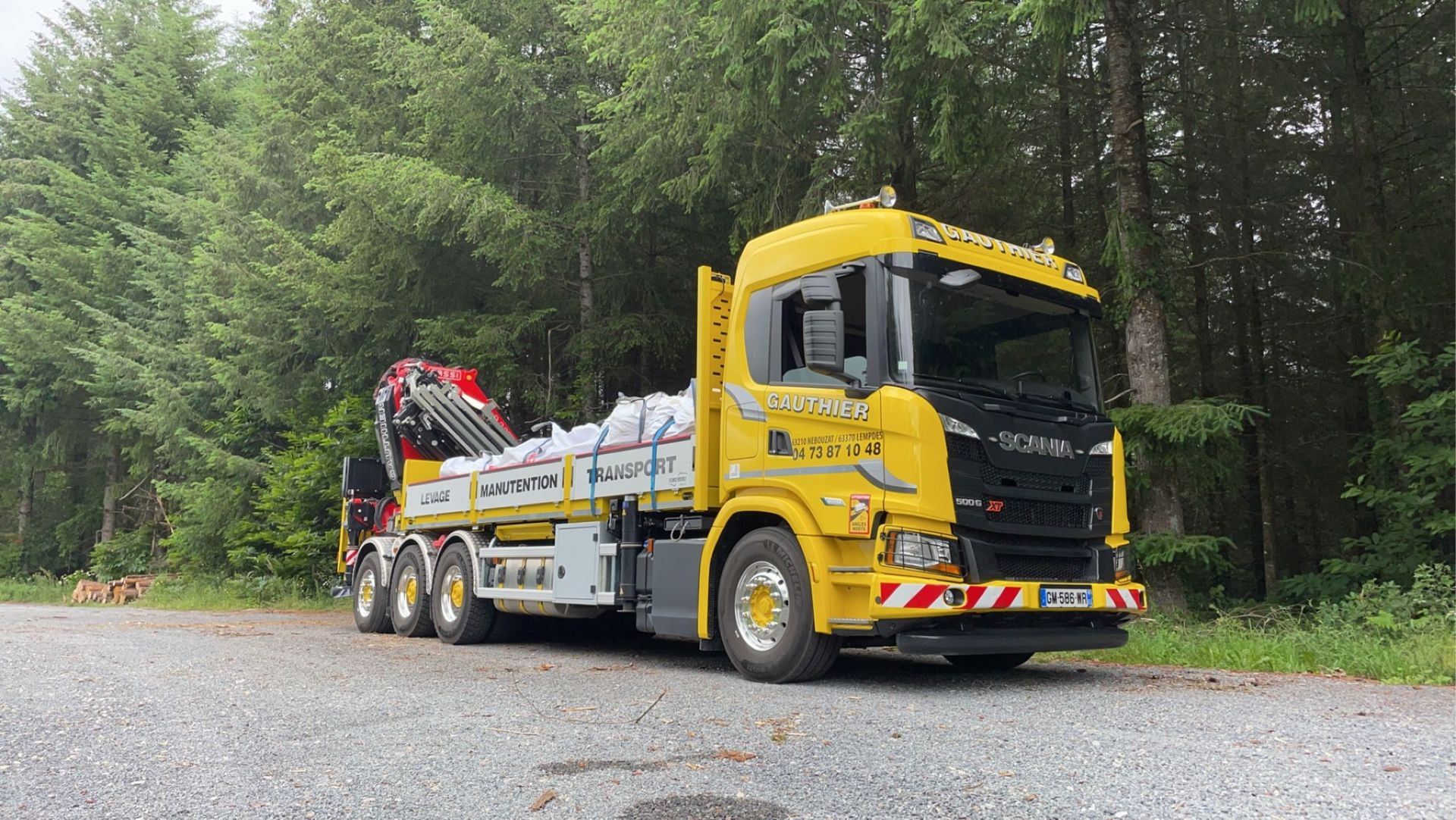 Camion jaune du Garage Gauthier devant une forêt