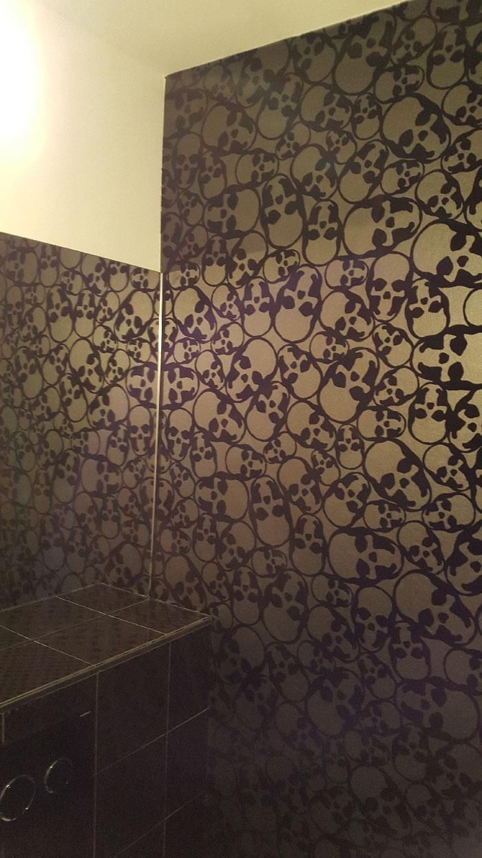 Ein Badezimmer mit einer violetten Wand und Totenköpfen darauf.