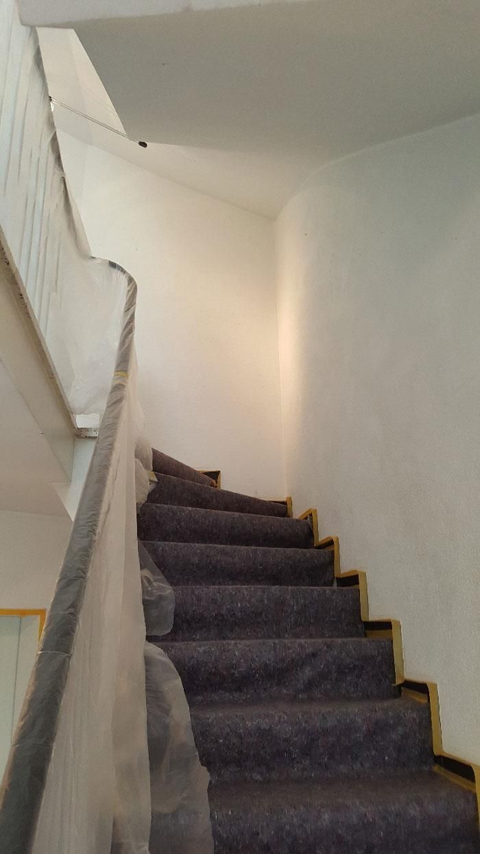 Eine Treppe mit einem violetten Teppich auf den Stufen und einer weißen Wand.
