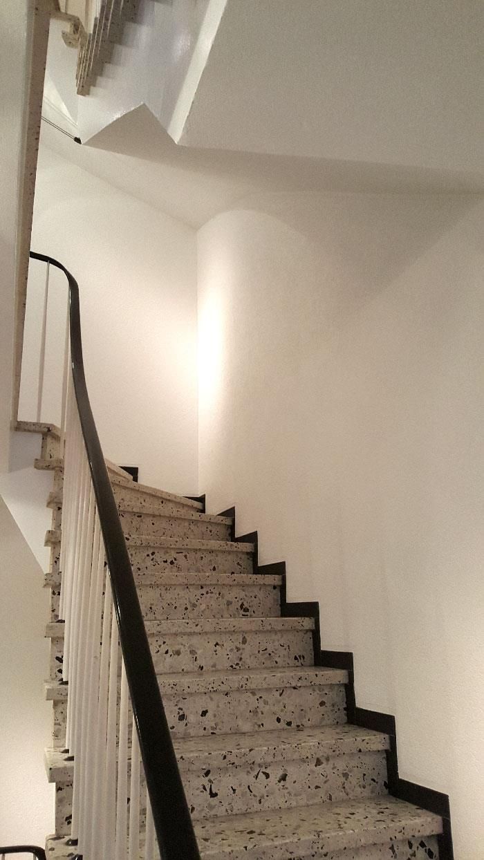 Eine Treppe mit schwarzem Geländer und weißer Wand