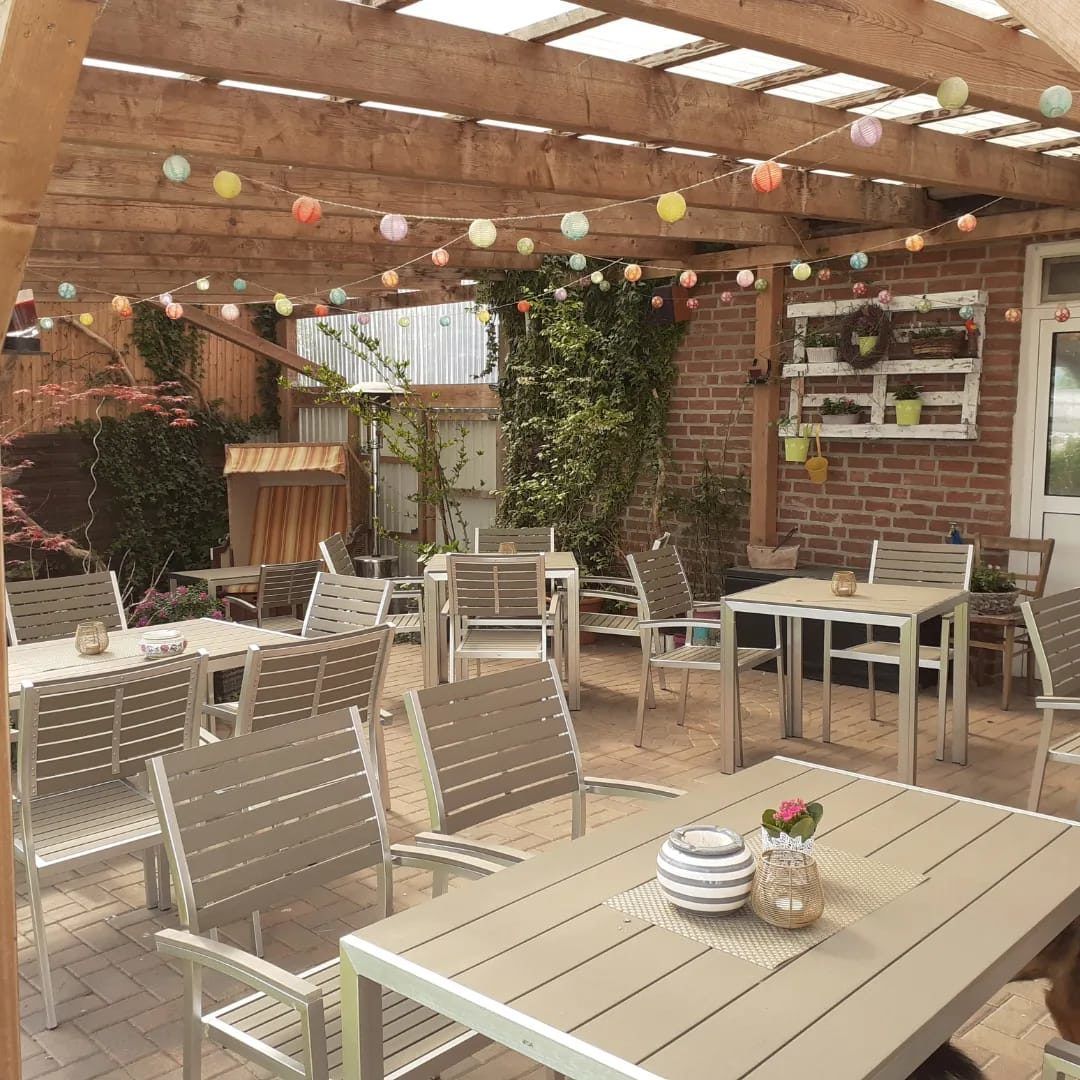 Eine Terrasse mit Tischen und Stühlen unter einer Pergola