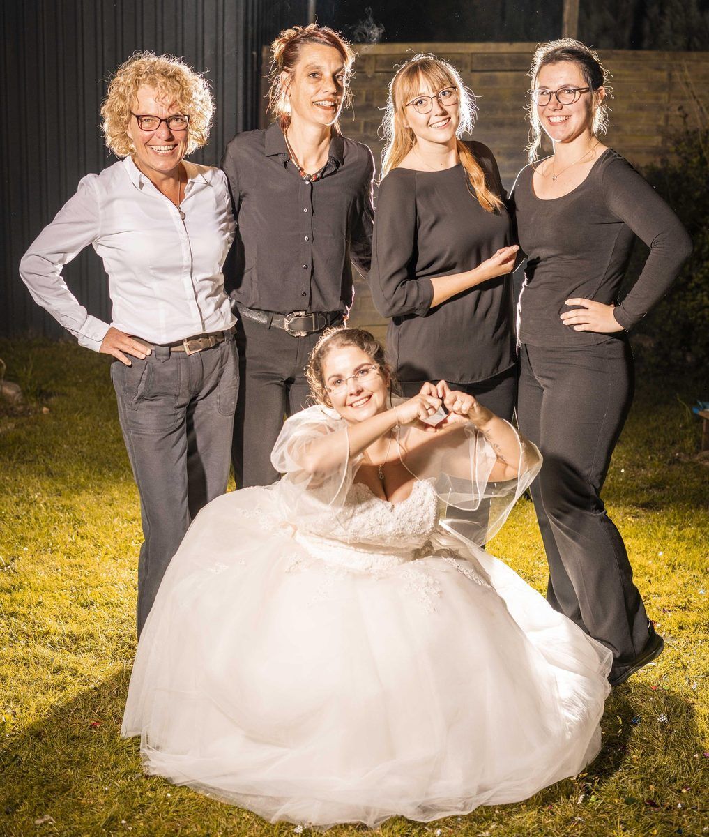 Eine Gruppe von Frauen posiert für ein Foto mit einer Braut im Brautkleid.