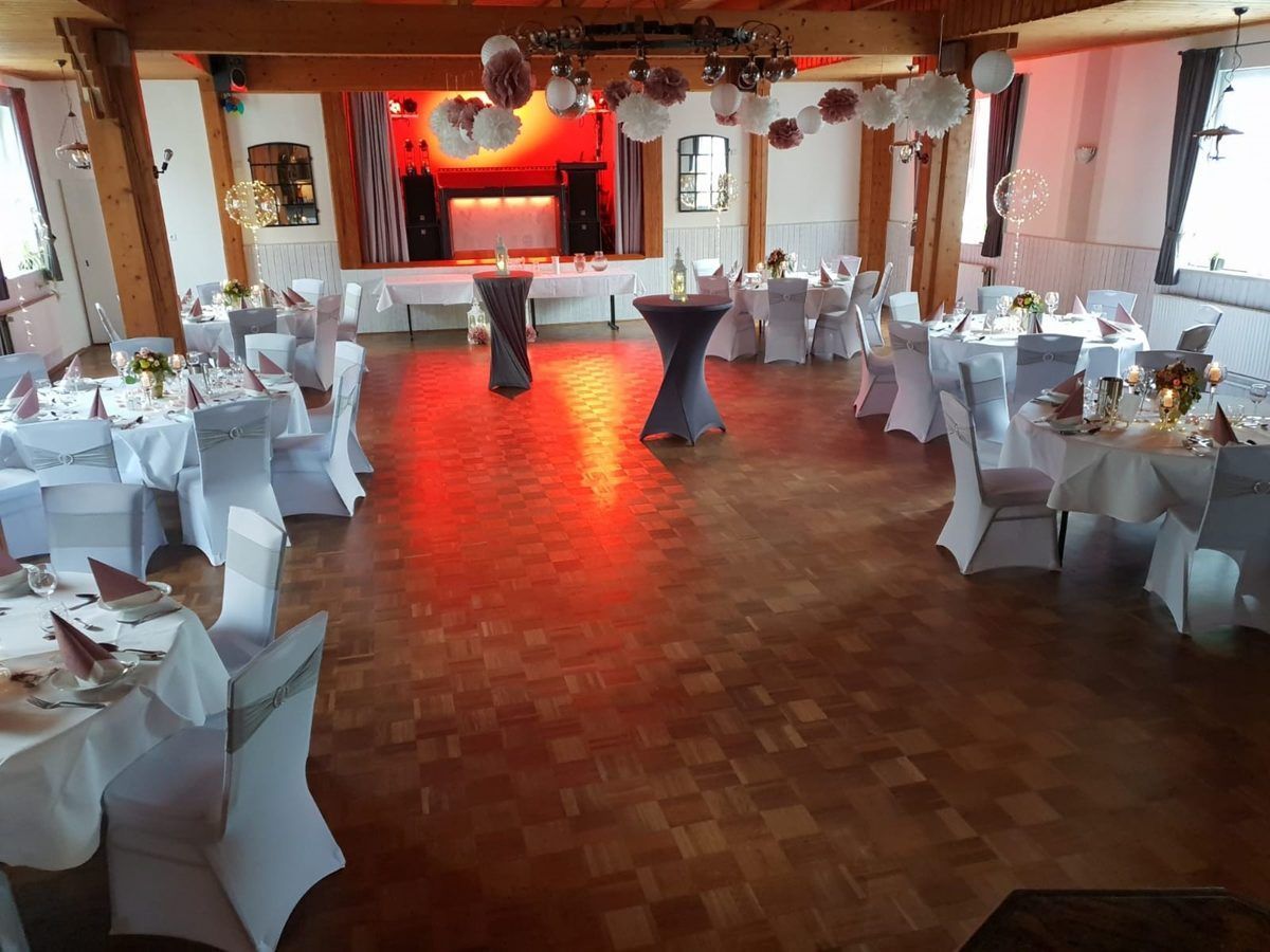 Ein großer Raum mit Tischen und Stühlen für einen Hochzeitsempfang