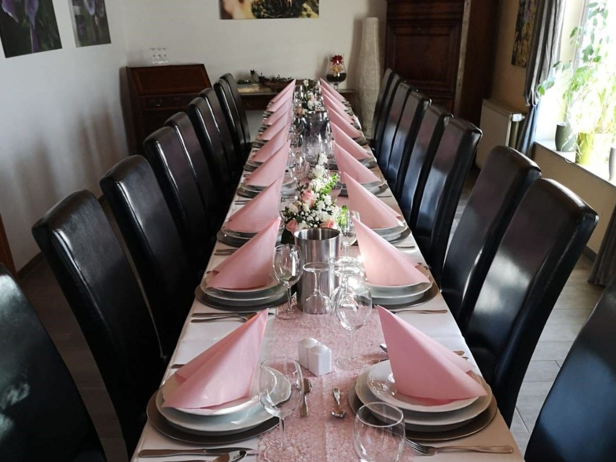 Ein langer Tisch mit rosa Servietten und Tellern darauf