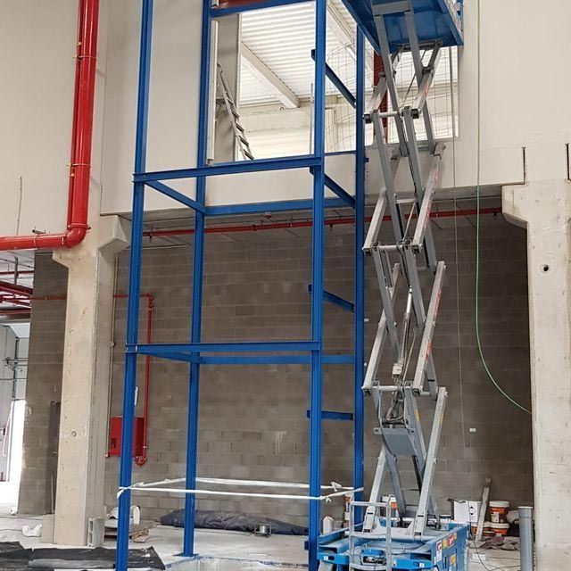 Un elevador de tijera azul está en un edificio en construcción