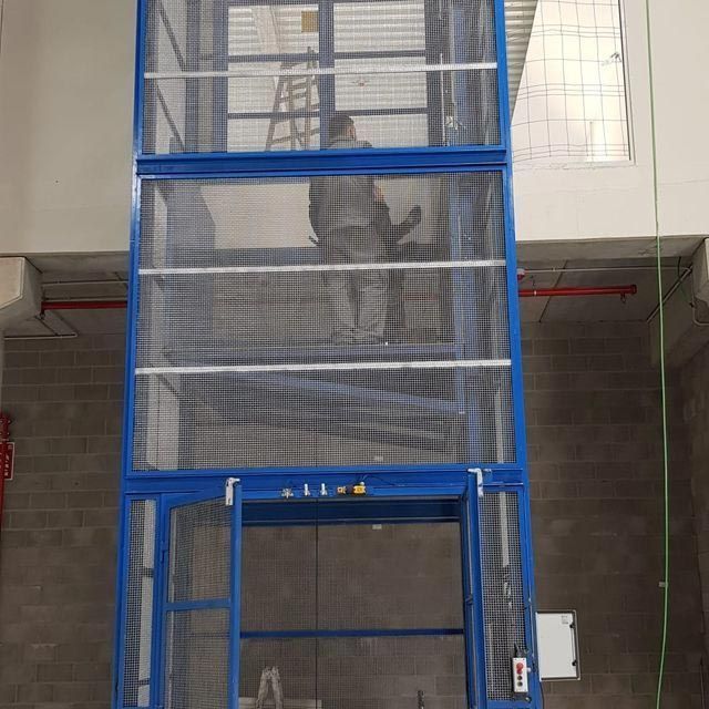 Un hombre está parado encima de un ascensor azul.