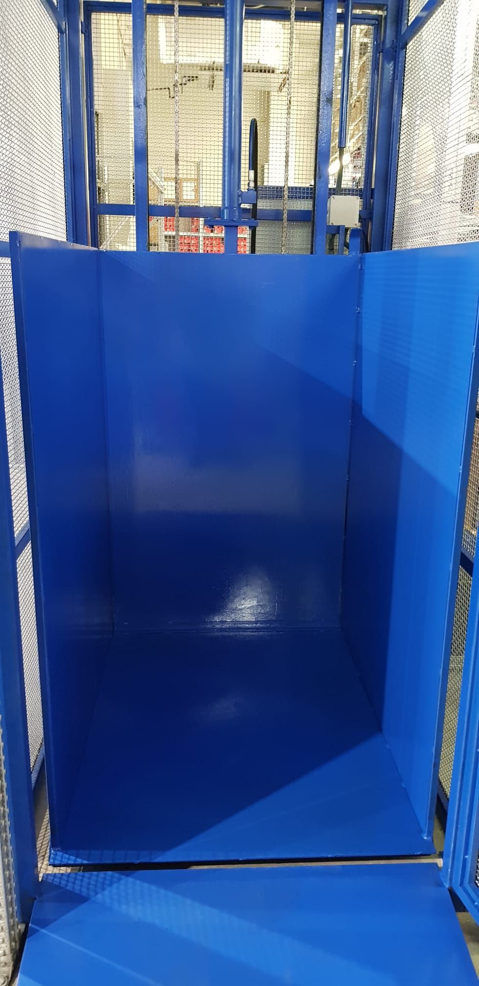 Una caja azul se encuentra en una jaula en un almacén.