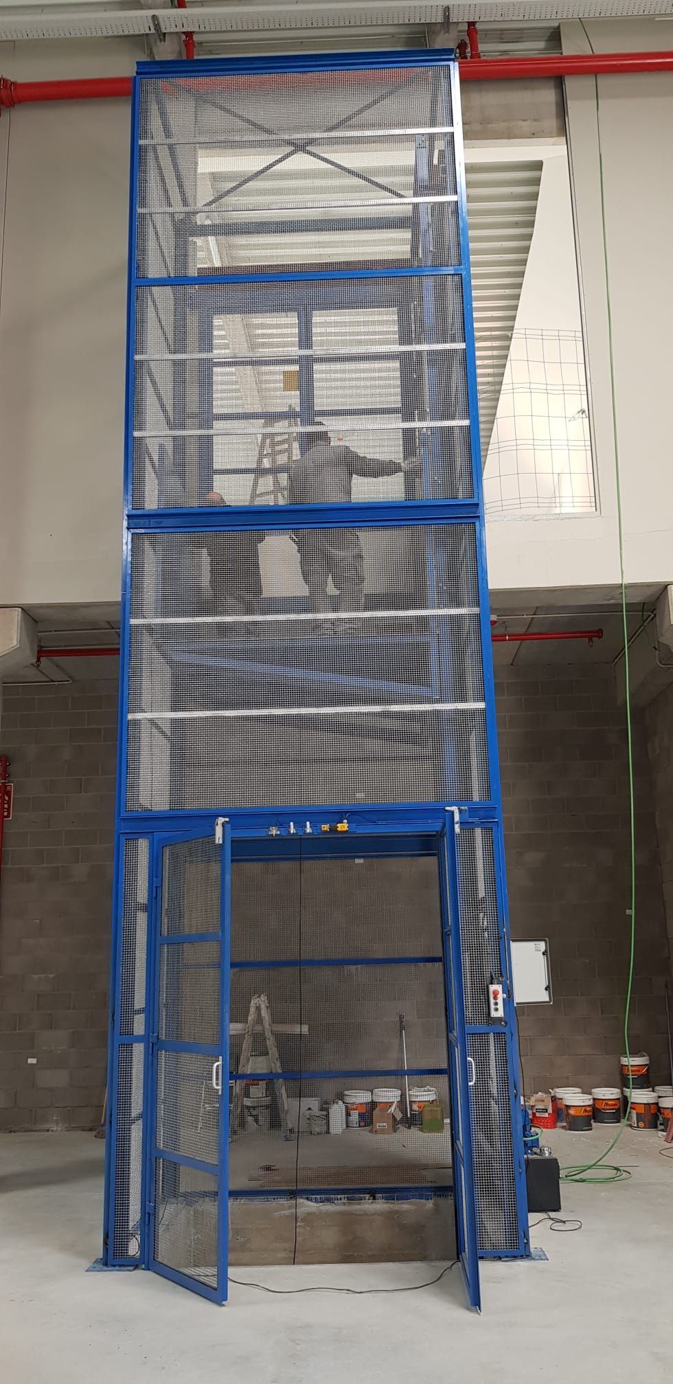 Una jaula azul con escaleras que conducen a ella en un edificio.