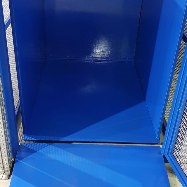 Una caja azul con la puerta abierta y una valla de metal alrededor.