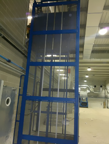 Un ascensor azul en un edificio con una pantalla transparente.