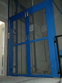 Hay un ascensor azul con puerta de cristal en un edificio.