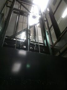 Mirando hacia arriba a un ascensor en un edificio con muchas ventanas.