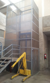 Una grúa amarilla está delante de una escalera en un almacén.