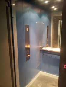 Un ascensor azul con un espejo y botones en la pared.