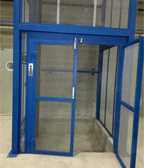 Un ascensor azul con la puerta abierta y una pared de ladrillos detrás.