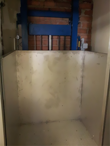 Un ascensor vacío con una puerta azul y una pared de ladrillos detrás.