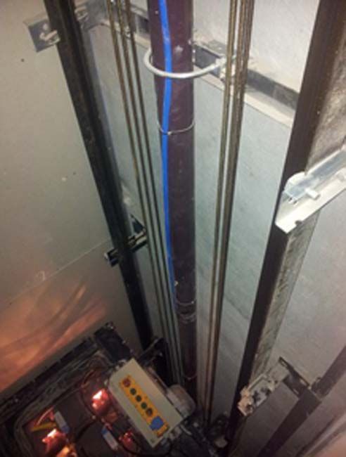 Un tubo azul cuelga del techo de un ascensor.