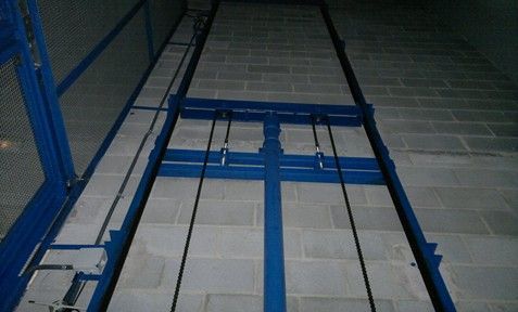 Un ascensor azul con una pared de ladrillos detrás.