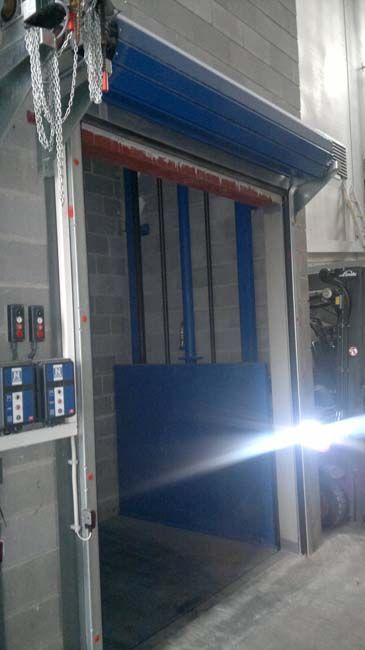 Una puerta enrollable azul está abierta en un almacén.