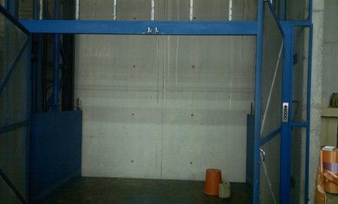 Una habitación vacía con una puerta azul y un cubo en el suelo.