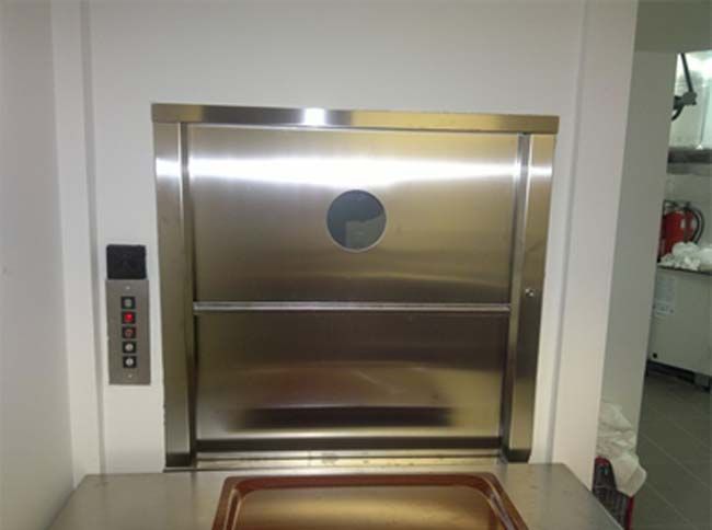 Un ascensor de acero inoxidable está integrado en una pared al lado de un fregadero.