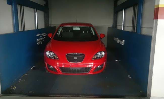 Un coche rojo está aparcado en un ascensor.