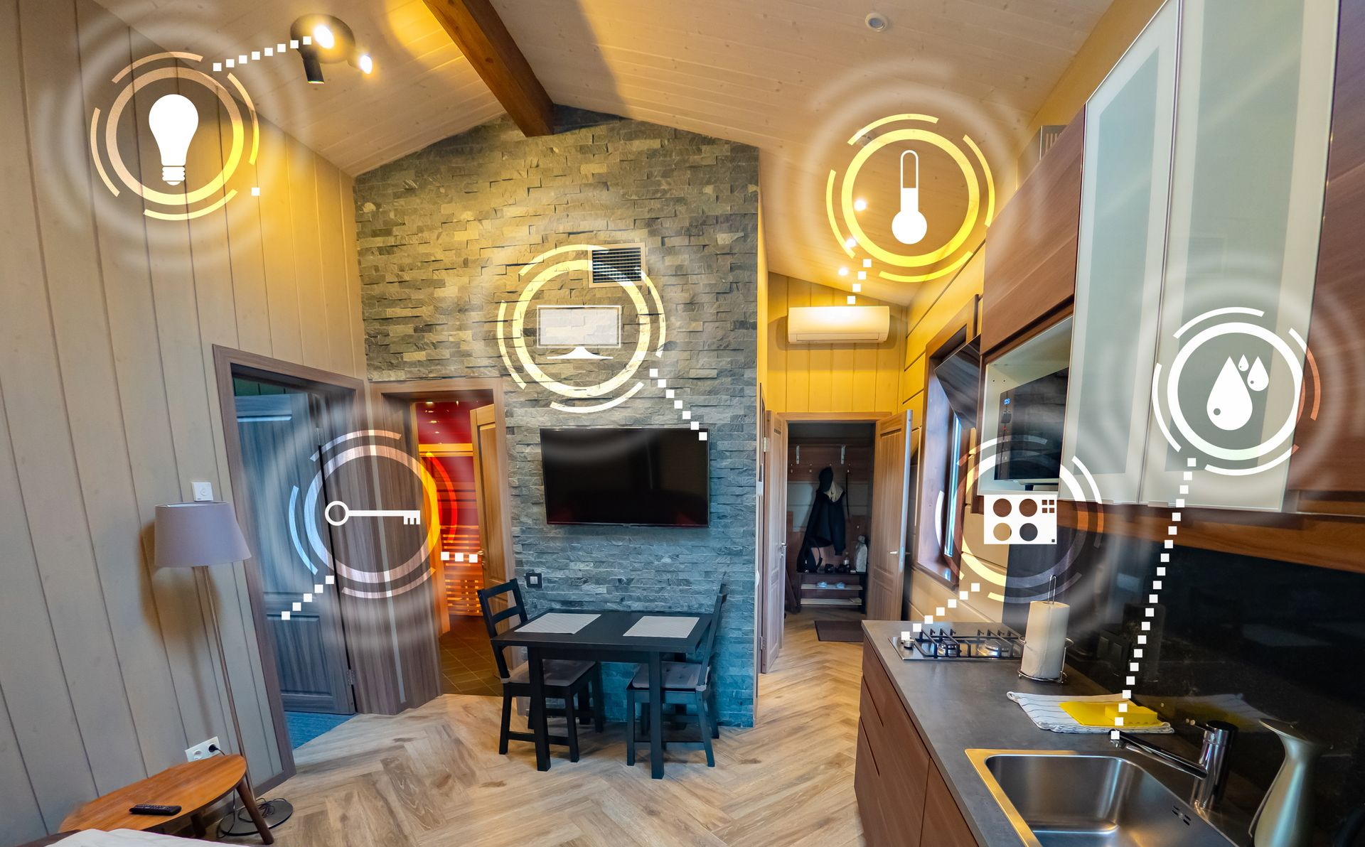 Cuisine et coin repas avec cheminée en pierre, table noire et luminaires suspendus aux tons chauds.