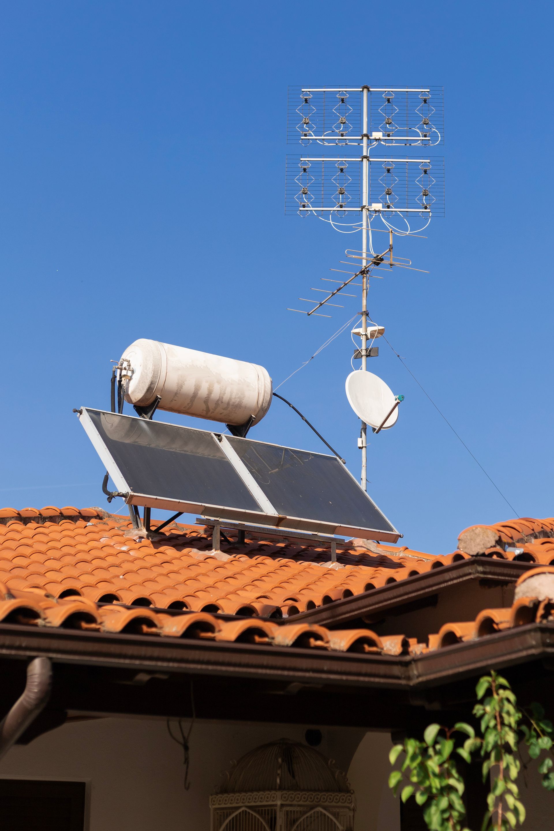 Panneau solaire sur le toit et réservoir cylindrique sous une antenne TV.
