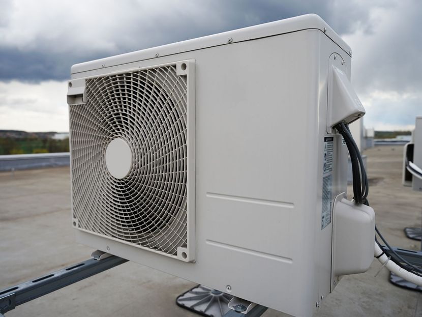Grande unité de climatisation extérieure blanche avec ventilateur, installée sur un toit.