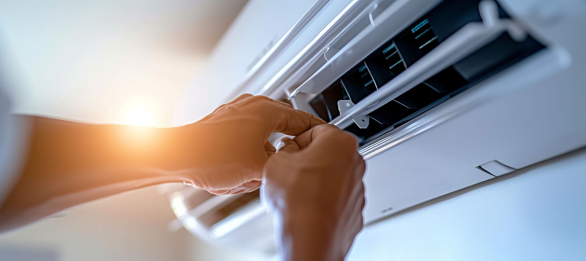 Des mains nettoient une grille d'aération de climatiseur avec un chiffon en plein soleil.
