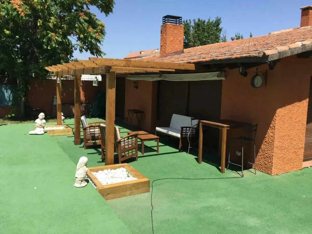 Una casa con una pérgola y sillas delante de ella.