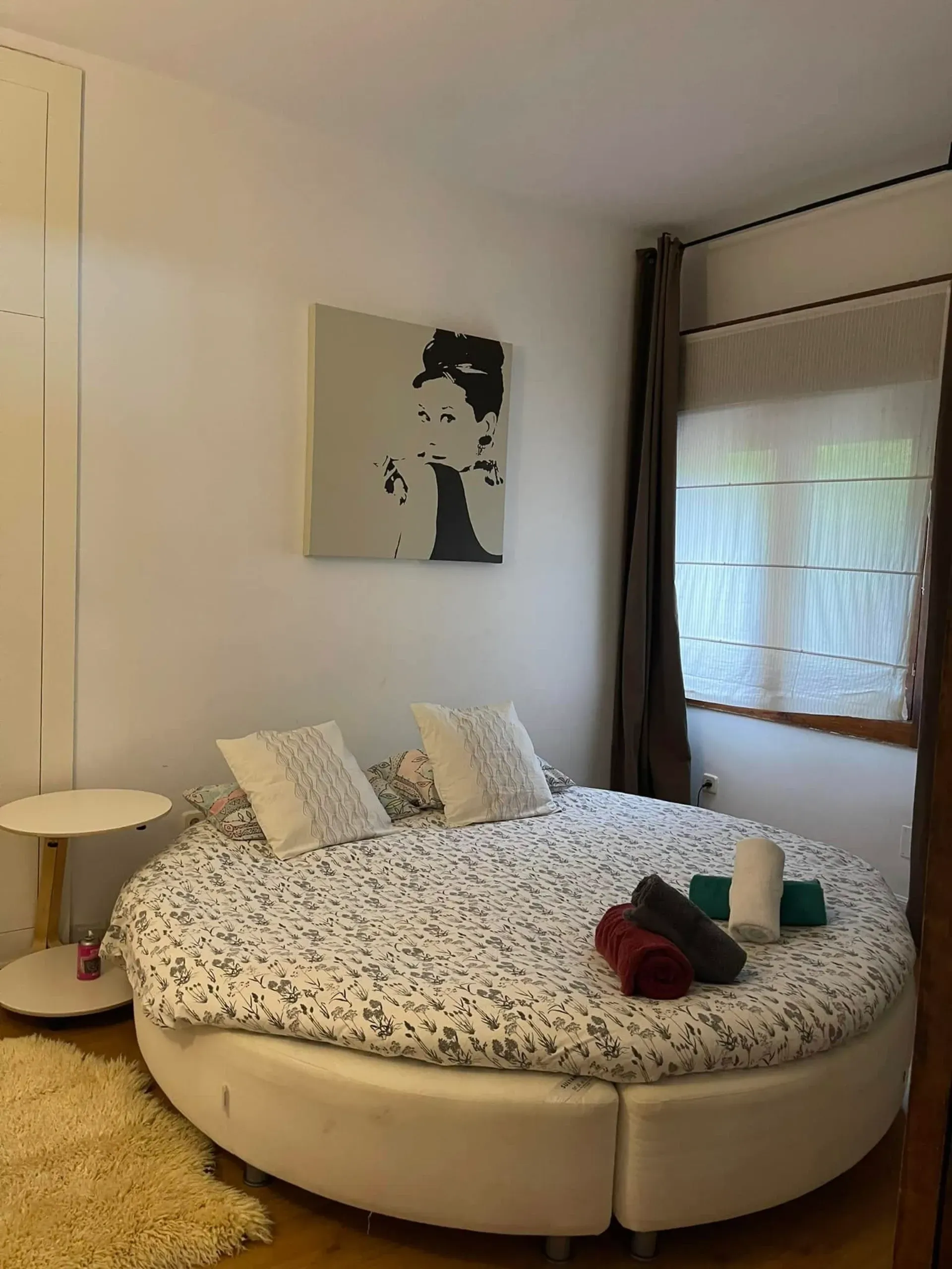 Un dormitorio con una cama redonda y un cuadro en la pared.