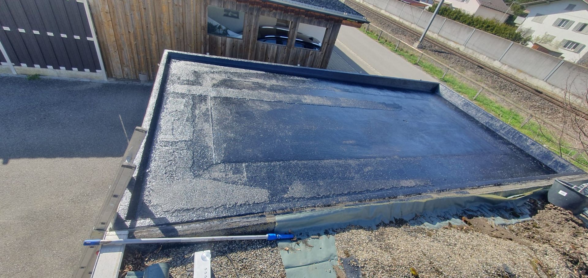 Ein Mann schaufelt mit einer Schaufel Schnee von einem Dach.