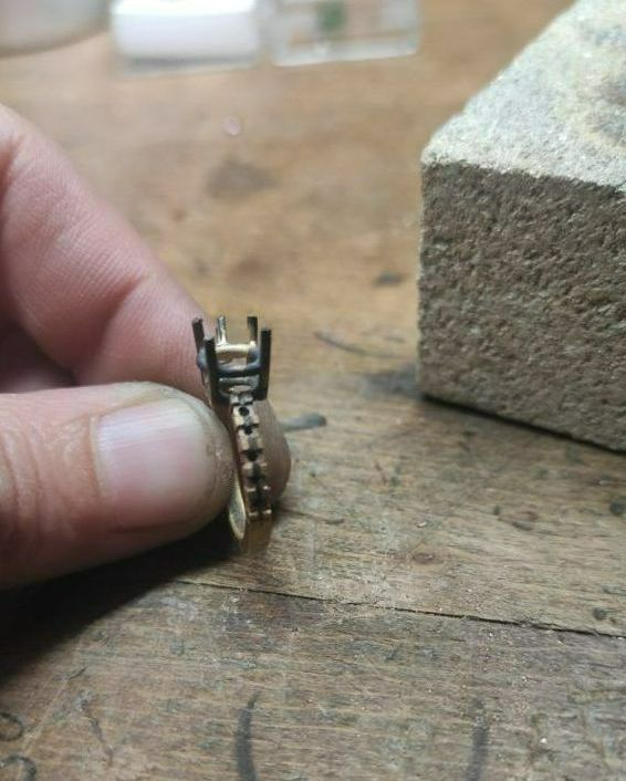 Une main tient une bague en réparation