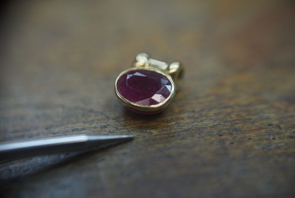 Un pendentif en or avec une pierre couleur bordeaux