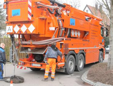 Kanalreinigung mit großem orangenen Fahrzeug