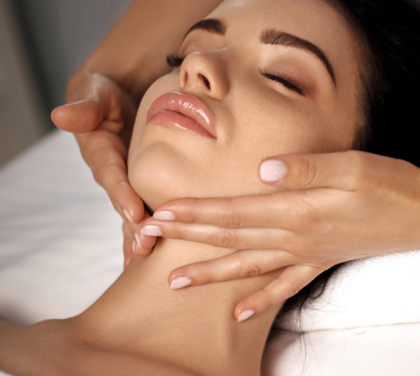 Femme recevant un massage du visage. Mains sur le visage et le cou, yeux fermés.