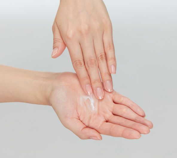 Mains appliquant de la lotion sur la paume, une main sur l'autre.