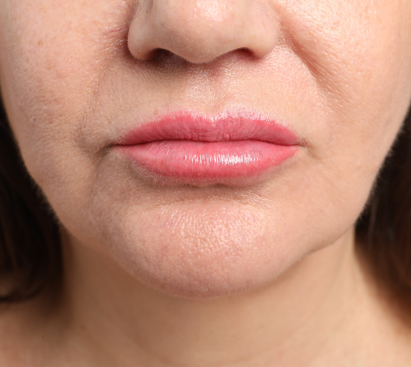 Gros plan du bas du visage d'une femme montrant des lèvres roses et une texture de peau.