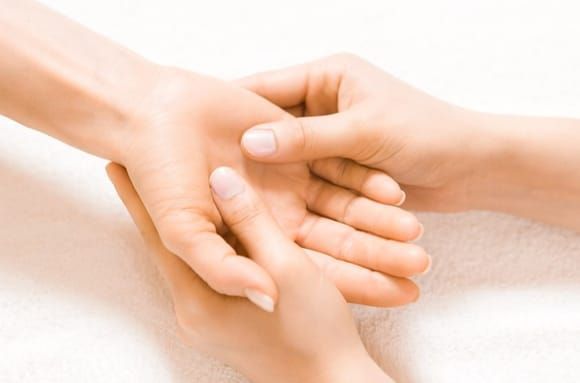 Mains tenant et massant une autre main, éventuellement un massage ou un traitement.
