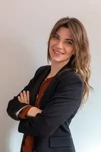 Flores blancas y plumosas en un jarrón con una mariposa posada en un tallo, contra una pared cálida.